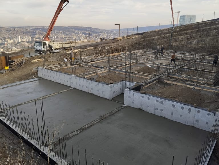 საძირკვლის ფილა და მონოლითური კედლები ქალაქის პანორამის ფონზე
